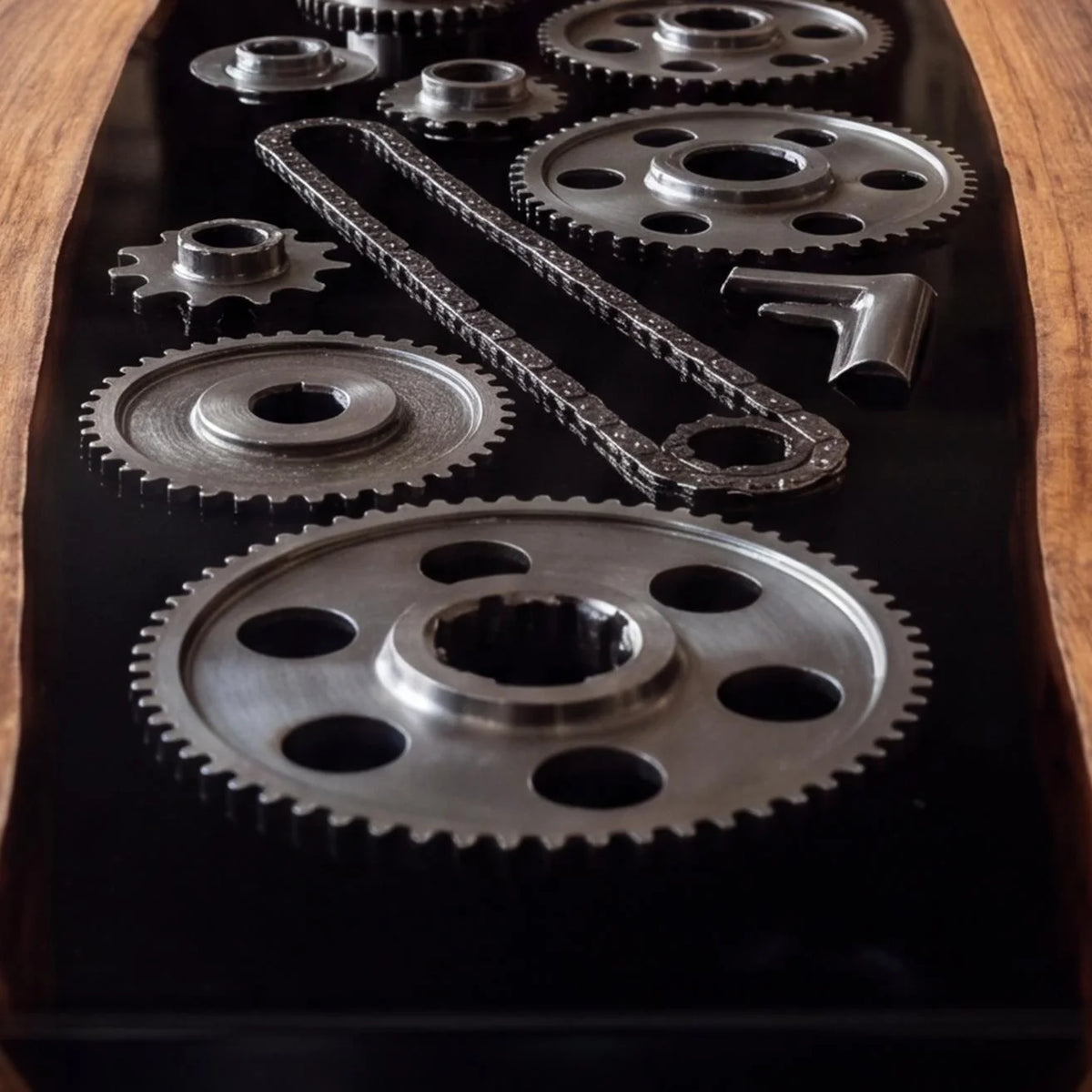 Close-up of metal gears and chain details set along glossy black resin